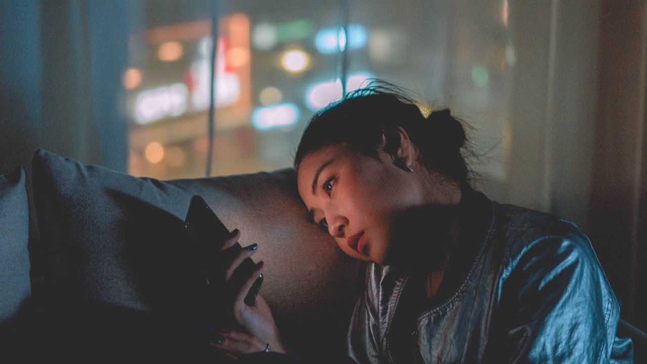 امرأة حامل تجلس متأملة بجانب النافذة، ضوء نهار ناعم، جو هادئ يرمز إلى الوحدة أثناء الحمل