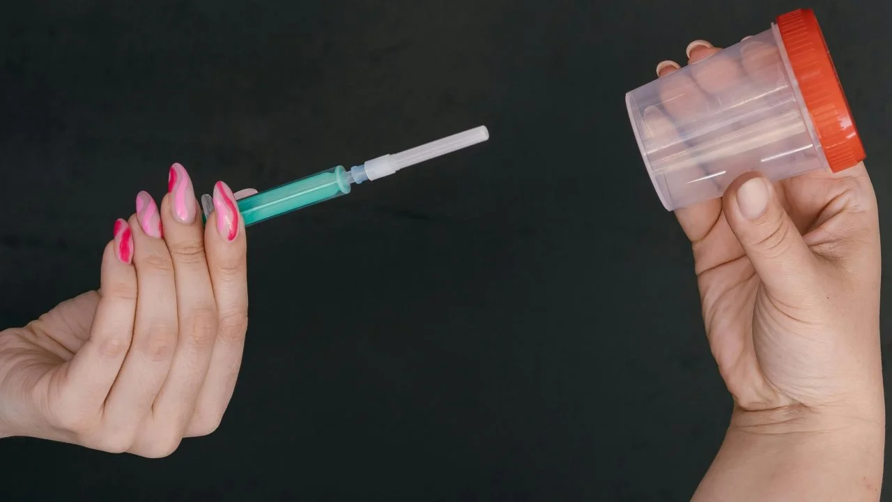 Jeringa sin aguja, recipiente estéril, guantes desechables y test de ovulación como partes simples de un kit de inseminación en casa