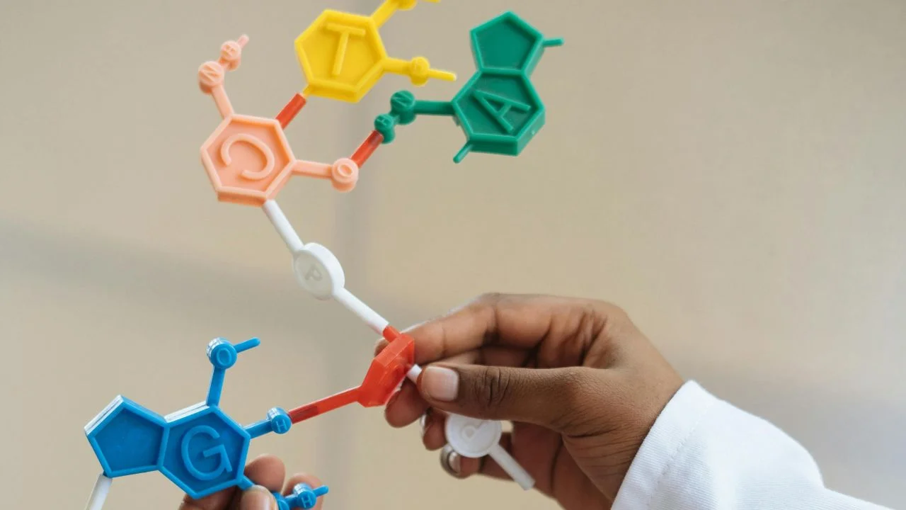 Hand hält ein Heim-DNA-Test-Kit vor neutralem Hintergrund