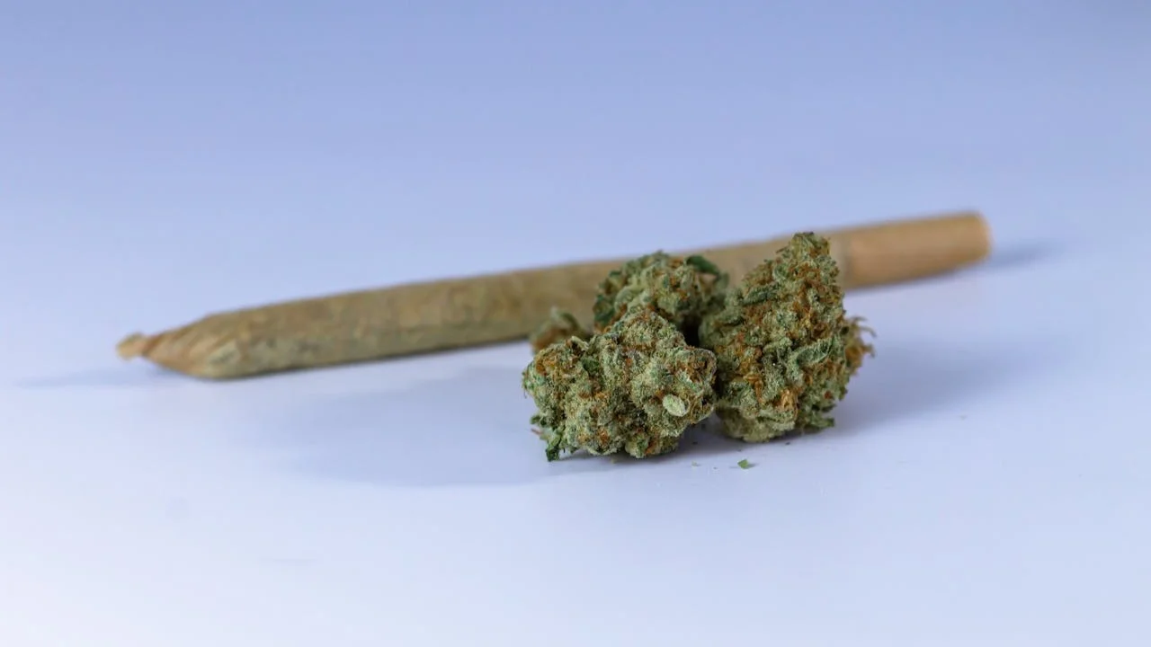فردی یک joint، یک vaporizer و محصولات cannabis-edibles را کنار لیوان آب و تقویم بارداری میگذارد