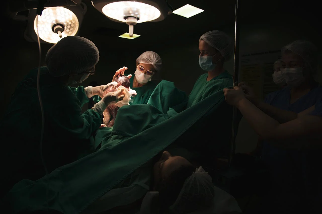 A person holding a newborn after a caesarean section, with a dressing on the lower abdomen in the foreground