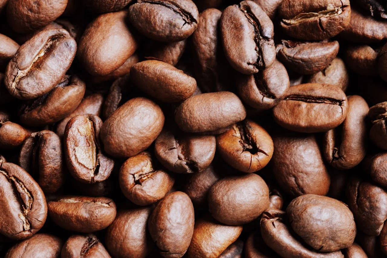 Eine schwangere Person steht in der Küche mit einer Kaffeetasse und überlegt, wie viel Koffein am Tag sinnvoll ist
