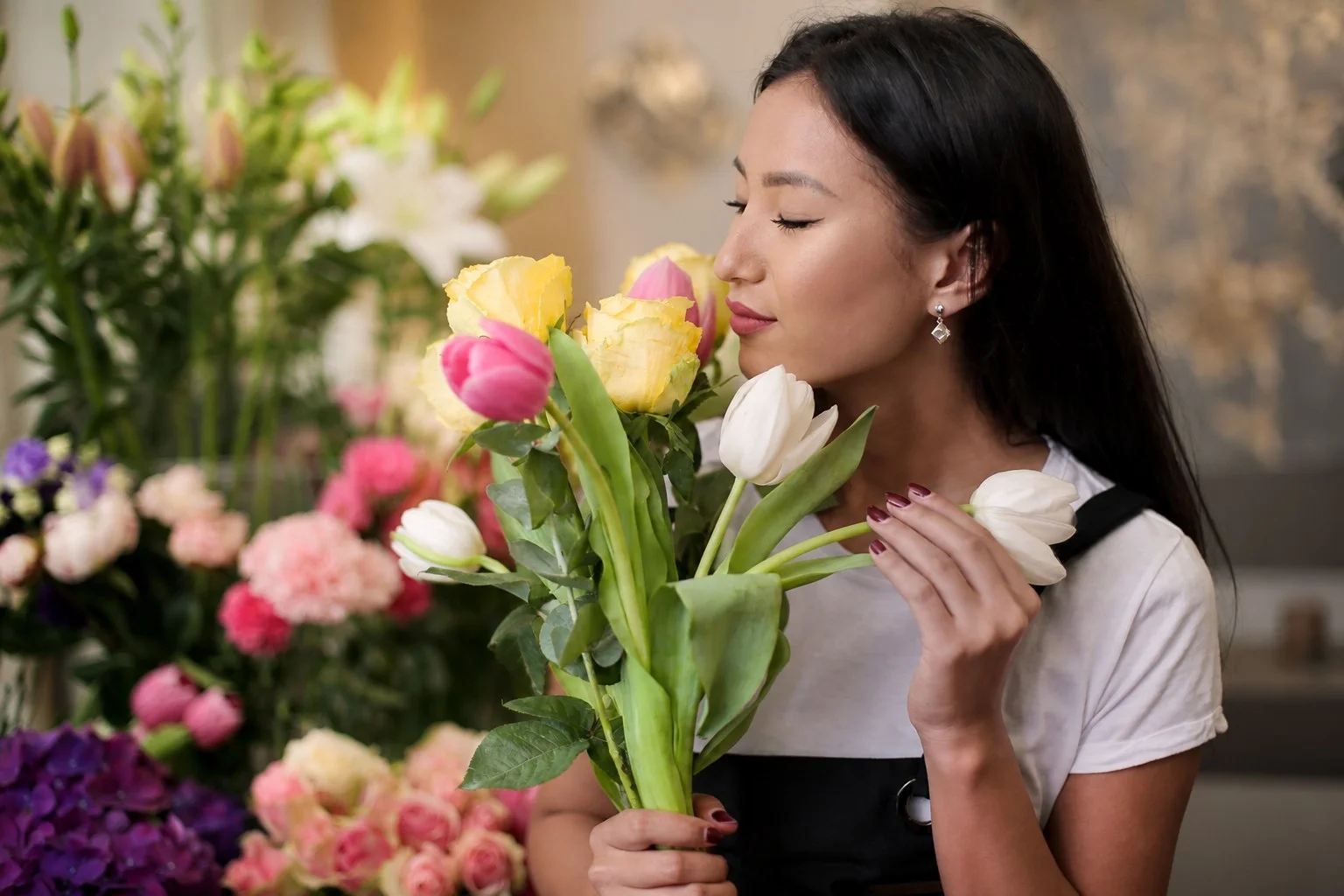 Eine Frau riecht an einem bunten Blumenstrauß als neutrales Symbol für subjektive Geruchswahrnehmung