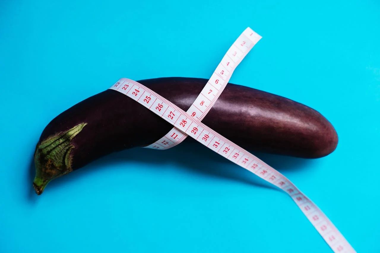 Aubergine mit Maßband vor blauem Hintergrund als Symbol für die Messung der Kondomgröße