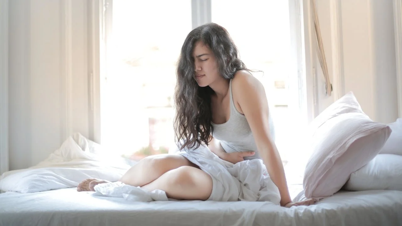Two people sit clothed and calmly next to each other on a couch, symbolizing conversation and putting things into context after sex