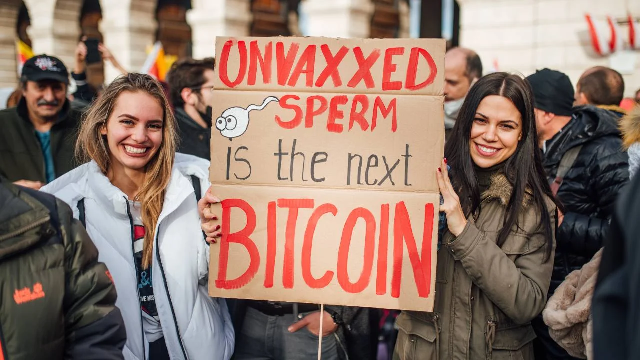 Two protesters in Vienna hold a sign reading Unvaxxed sperm is the next Bitcoin