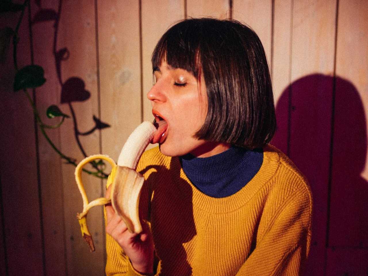 Symbolic image: A woman holds a banana as a non-explicit symbol for penis size. No explicit depiction.