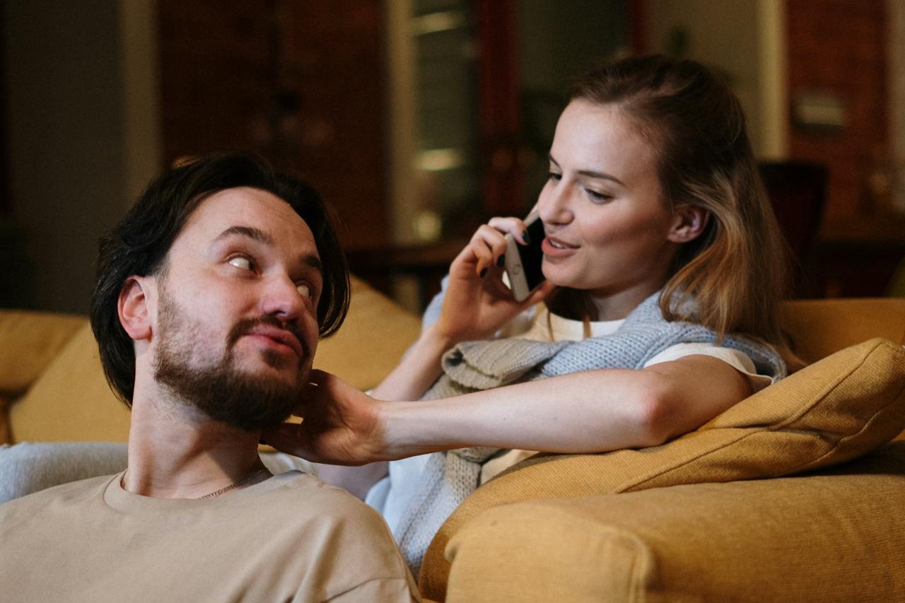 Two people sitting on a sofa having a calm conversation about boundaries, desires and safety.