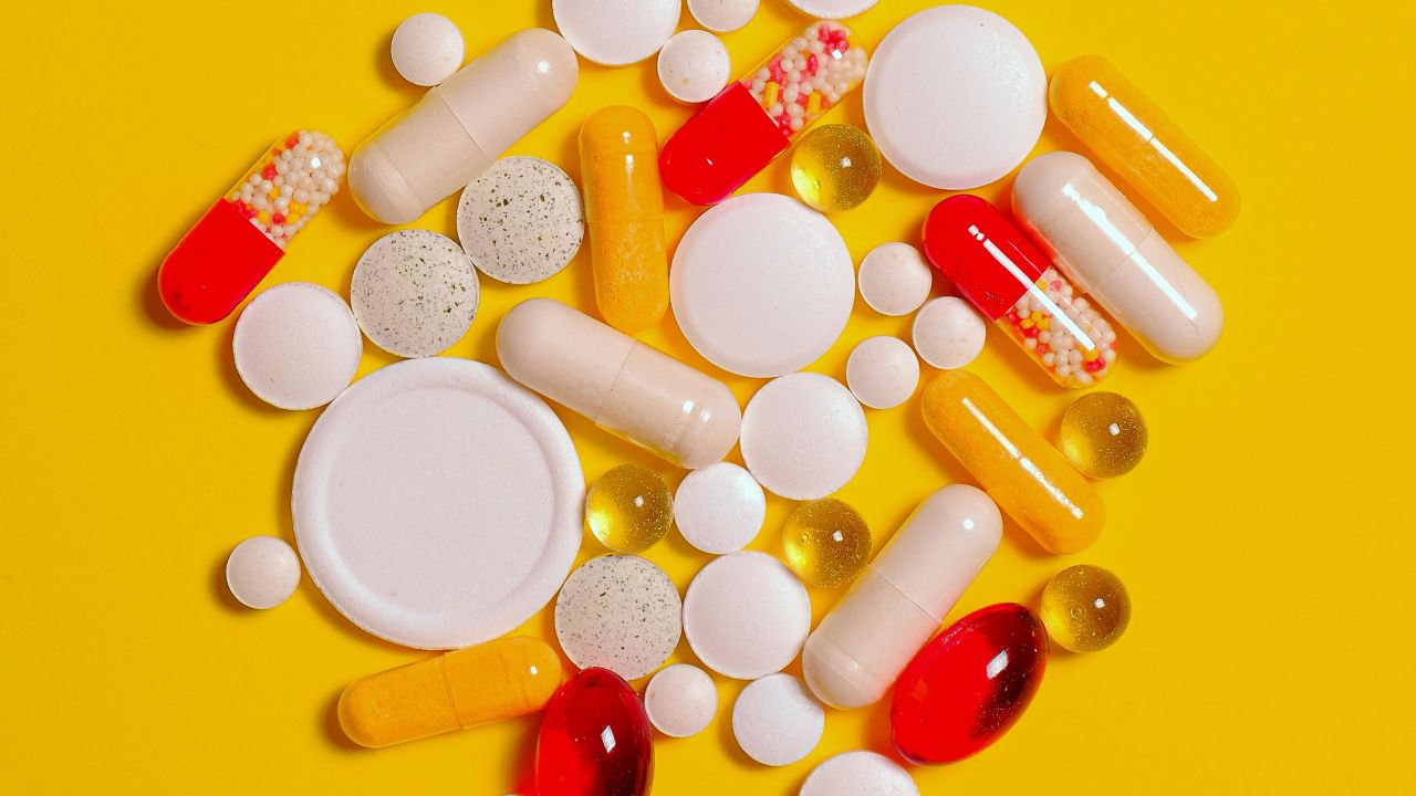 Capsule e compresse accanto a un quaderno come simbolo della scelta degli integratori per chi desidera una gravidanza