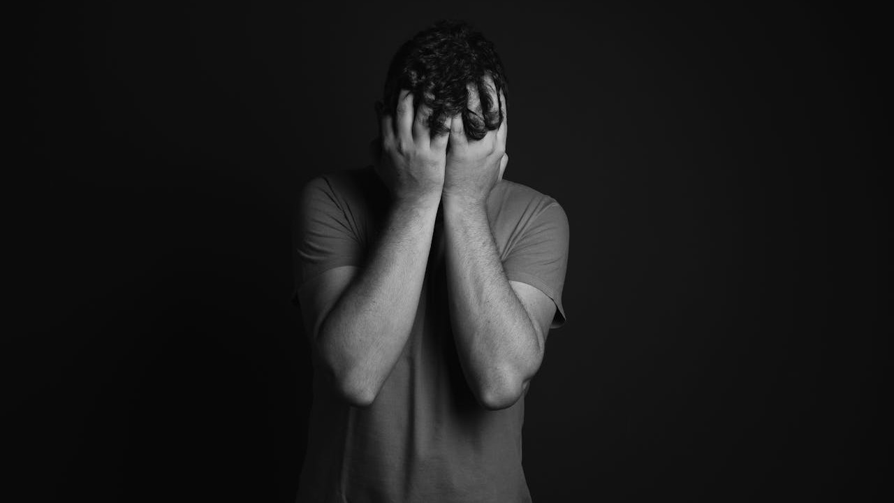 ベッドの端に考え込んで座る男性、隣にパートナーが座っている—プレッシャーではなく落ち着いた会話の場面